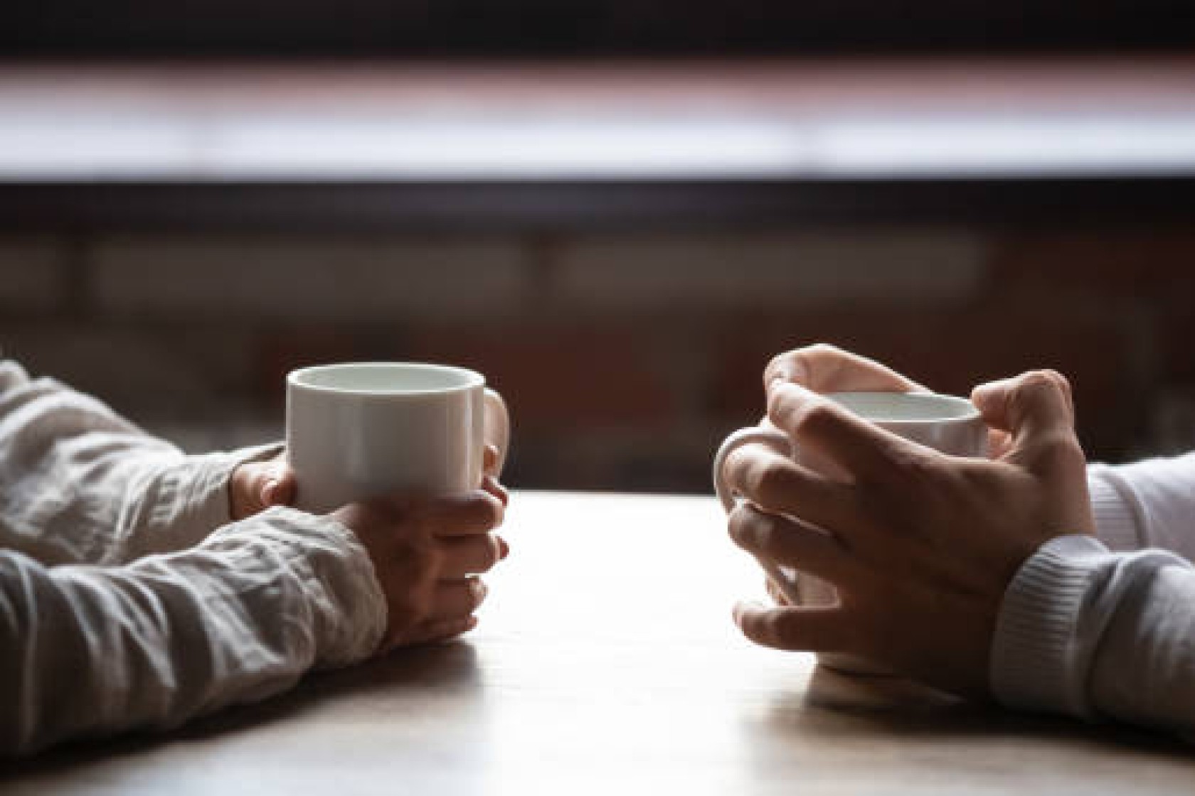 Close up woman and man sitting in cafe, holding warm cups of coffee on table, young couple spending weekend in cozy coffeehouse together, romantic date concept, visitors drinking hot beverages
