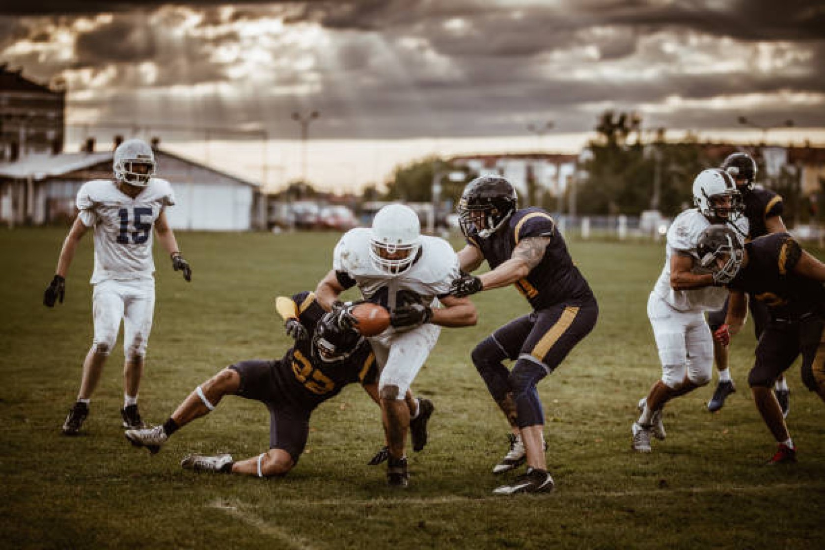 Determined American football player making a touchdown while passing through defensive players on playing field.